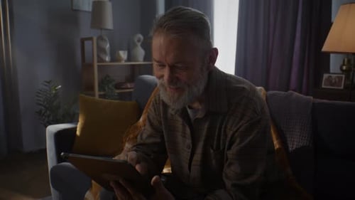 Senior Man Using Tablet on Couch Indoors