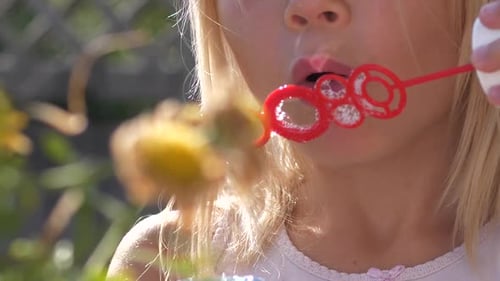 Girl Blowing Bubbles Outdoors on a Sunny Day