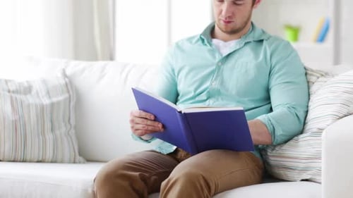 Leisure, Education and Home Concept - Man Reading Book and Sitting On
