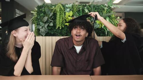 Female graduates wear a graduation hat to a Black friend in college.