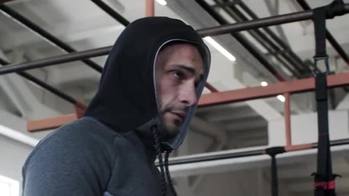 Determined Male Athlete Wearing Hooded Shirt Walking in Gym