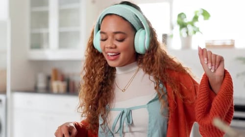 Happy Woman Dancing and Singing with Headphones in Kitchen