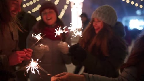 Cheerful Friends Have Fun Partying with Sparklers in Hands at Christmas Market People Jump and Dance
