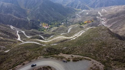 Winding dirt road descends to autumn valley in dramatic switchbacks