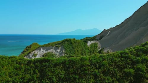 Breathtaking aerial view of dramatic green mountains and blue ocean. Clip.