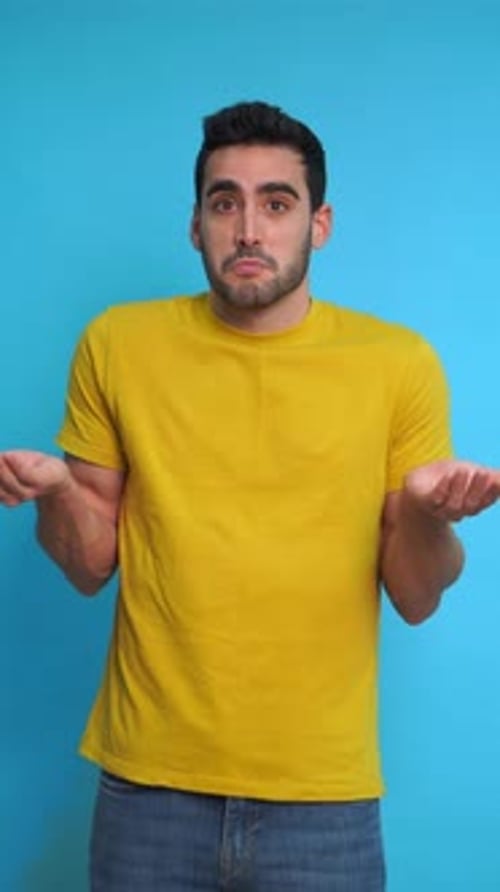 Young Adult Shrugs Against Blue Background