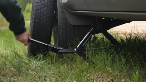 a Jack Lifts a Car on the Side of the Road to Change a Tire