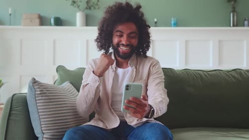 Young Man Celebrates While Using Smartphone