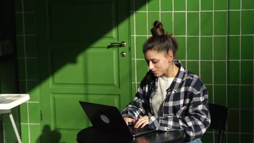Beautiful Young Woman Sitting at Table with Laptop in Cafe Working Online Typing and Smiling