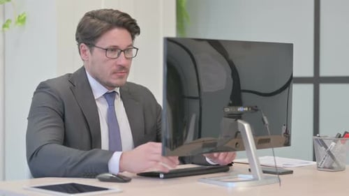 Man Working at Computer Smiling at Camera