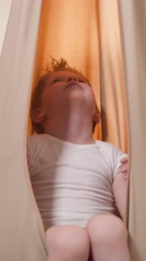Child Standing Inside Hanging Fabric Looking Upward