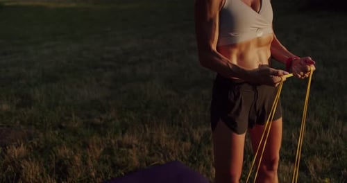 Woman Exercising Outdoors with Resistance Band at Sunset