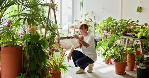 Woman Waters Plants in Indoor Garden