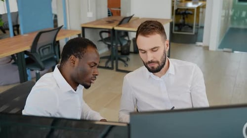 Two Diverse Traders Sitting at Desk at Office Together Monitoring Stocks Data Candle Charts on