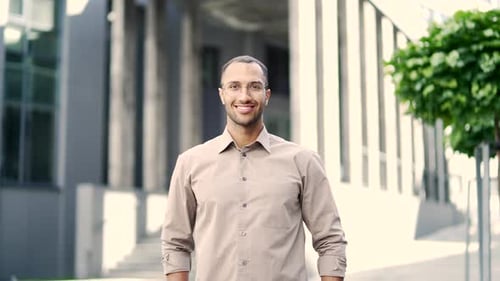 Smiling Man Standing Outdoors Near Modern Building
