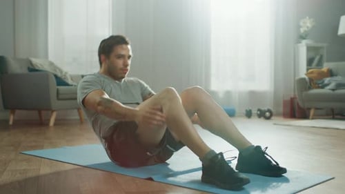 Starker, athletisch fitter Mann in T-Shirt und Shorts macht zu Hause in seinem Spa Bauchmuskelübungen