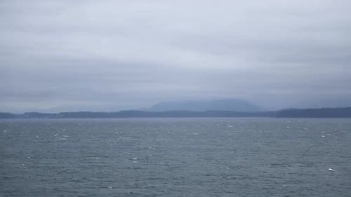 Sea waves and mountain shrouded in mist on background. Static shot