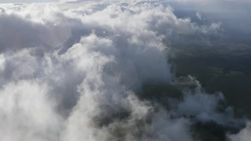 High aerial view over clouds moving over the landscape of Maui, Hawaii on a sunny day.