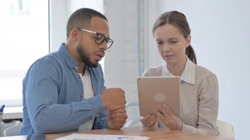 Man and Woman Discussing Tablet in Modern Office
