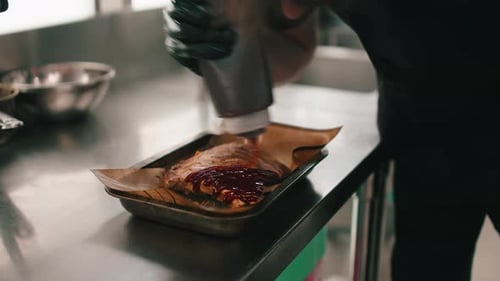 Chef Adding Sauce to Ribs in Kitchen