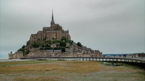 Timelapse of Mont Saint Michel with tourists walking in and out of the city on a newly constructed b