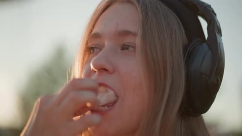 Girl with Headphones Eats Cotton Candy Outside