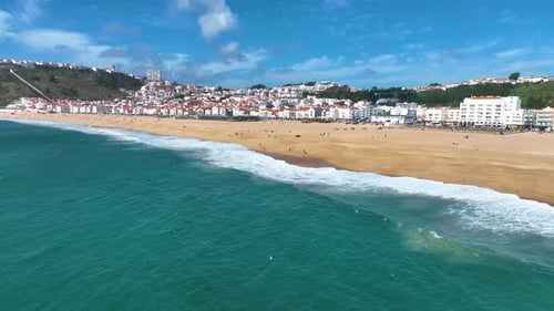 Nazare beach shoreline with town and cliffs in view