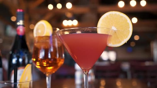 Fruity cocktails adorned with orange slices and wines in a warm romantic lounge, slider 4K