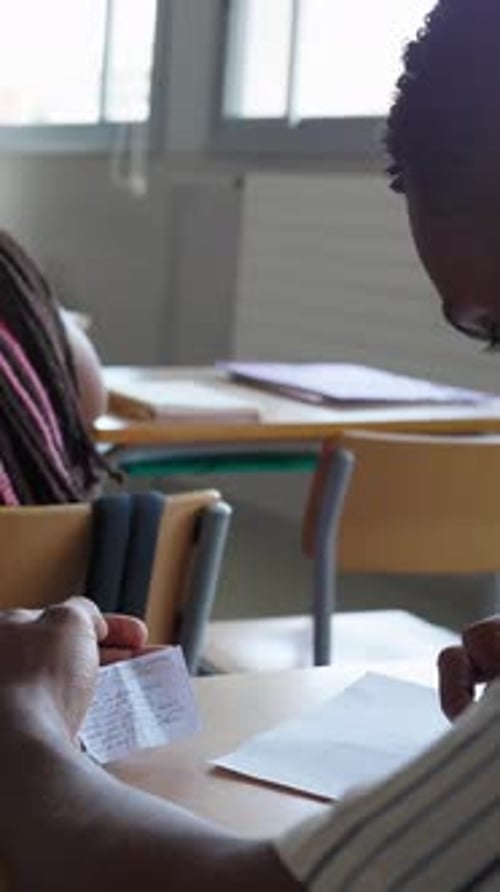 Joven adolescente haciendo trampa durante un examen en el aula de la escuela secundaria