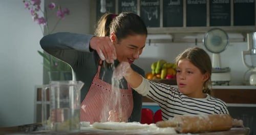 Portrait of Mother and Daughter in the Kitchen Baking Together. Playful Little Girl and her Mom