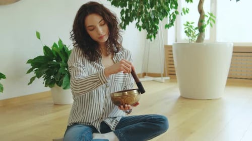 Woman Meditating with Singing Bowl in Bright Home