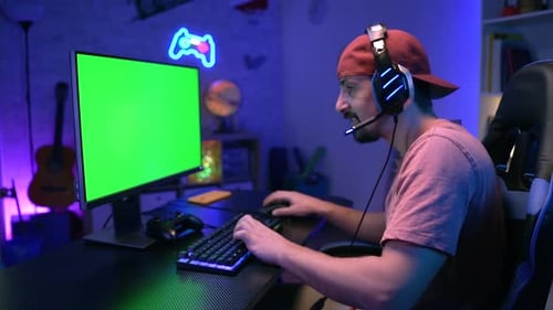 Happy Gamer Streaming and Playing Online Video Game on Computer Green Screen Colorful Neon Lights