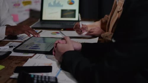 Businesspeople working overtime on laptop and paperwork in the office.