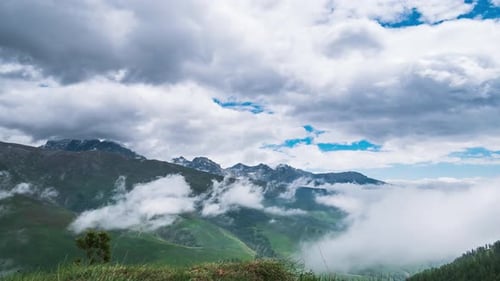 Time lapse, moving clouds in the valley below mountain ridges and peaks of the Alps. Majestic snow c