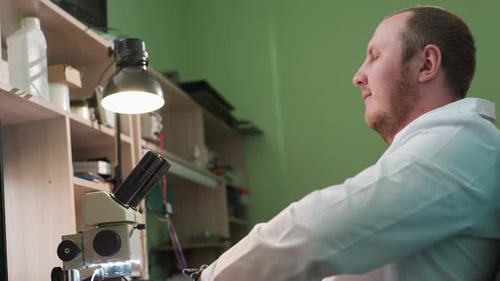 Scientist Looks Into Microscope in Workplace Setting