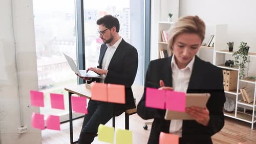 Team Brainstorming Session Using Sticky Notes on Glass Board in Office Setting