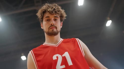 Porträt eines kaukasischen Basketballspielers, der ernsthaft in die Kamera schaut und den Ball festhält
