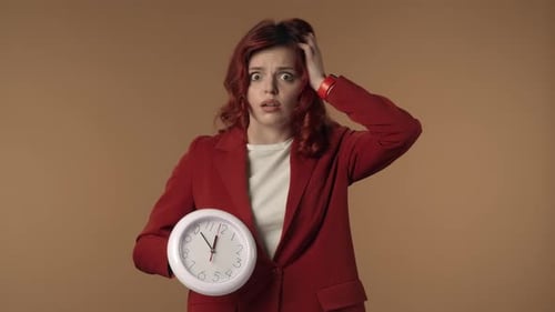 Mittleres isoliertes Video einer schockierten und besorgten jungen Frau, die auf die Uhr schaut und den Kopf schüttelt