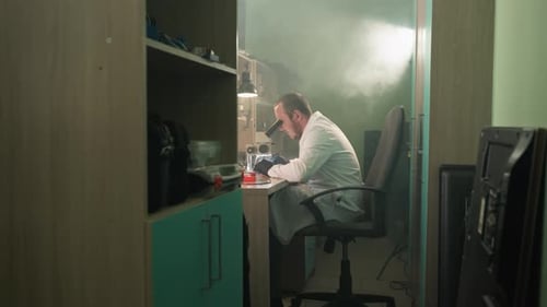 Scientist Looks Through Microscope in a Laboratory