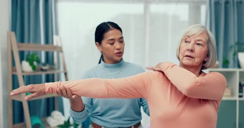 Woman Stretching Senior Woman's Arm in Home