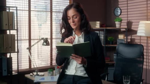 Woman Writes in Notebook in Professional Office