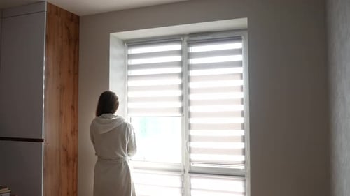Woman Opens Window Blinds in the Morning