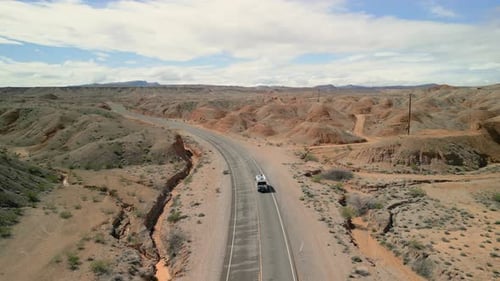 Tracking shot following as an RV drives along a quiet road in the desert.