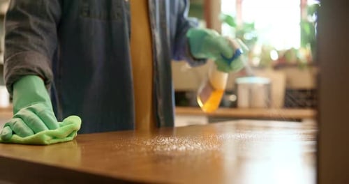 Person Cleaning Wooden Surface With Green Gloves