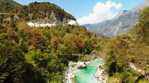 Fluss Soca, Slowenien: Drohnenaufnahme des klaren Flusses, der Hängebrücke, des Waldes und des fernen Berges