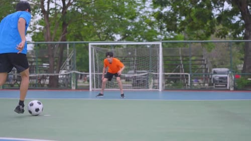 Zwei asiatische Sportler beim Fußballspielen im Freiluftstadion.