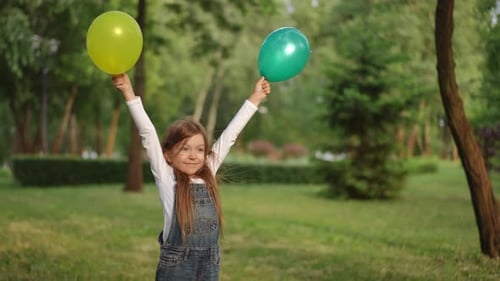 A Joyful and Playful Child with Colorful Balloons Enjoying Delightfully in a Lush Green Park