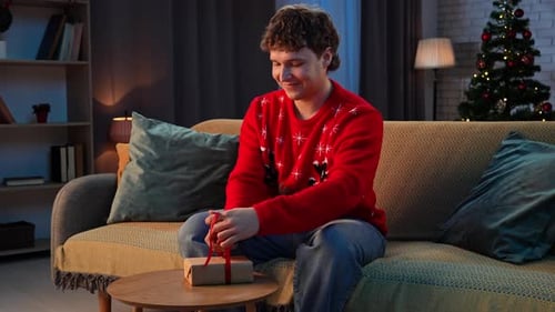 Smiling Man Unwraps Christmas Gift Indoors