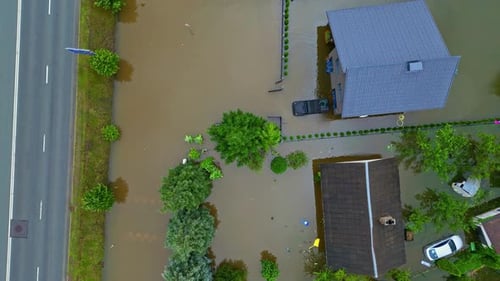 Flooded suburban homes and streets surrounded by brown floodwaters, aerial view