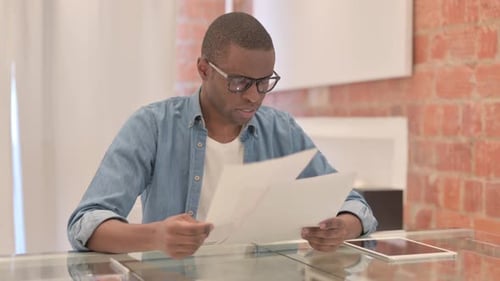 Focused Man Reads Documents at Modern Home Desk